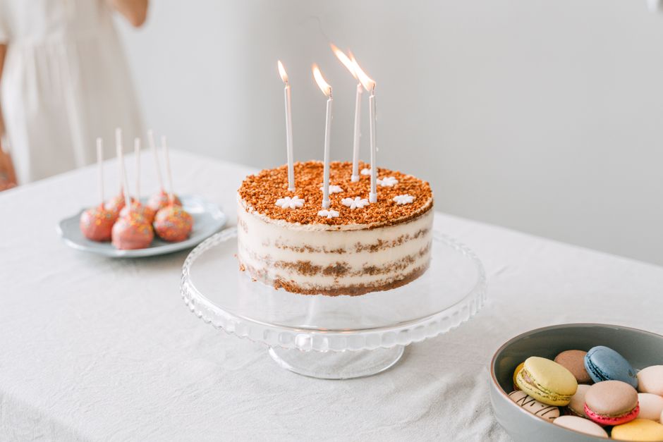 Gâteau d'anniversaire décoré avec des bougies, accompagné de macarons et de sucettes sur une table élégante.