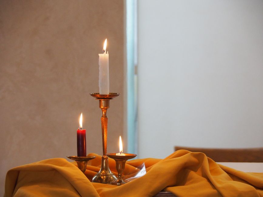 Bougeoirs avec trois bougies allumées sur une nappe jaune, créant une ambiance romantique pour un anniversaire.