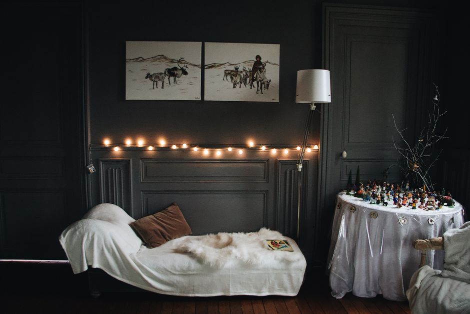 Salon cosy avec un canapé blanc, des guirlandes lumineuses et des tableaux au mur, créant une ambiance romantique.