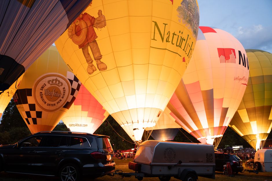 Montgolfières illuminées lors d'un festival, créant une ambiance chaleureuse et festive en soirée.