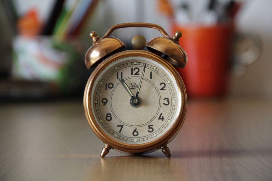 Réveil vintage en métal cuivré sur un bureau, symbolisant l'urgence des cadeaux de dernière minute.