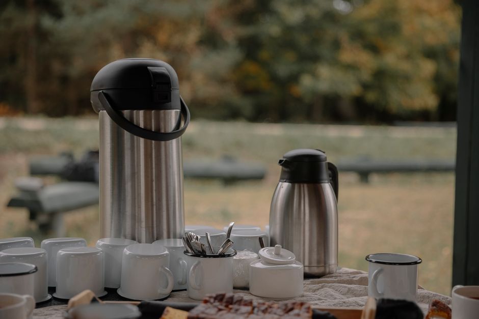 Table dressée avec des tasses blanches, une théière et des sucreries, en plein air, ambiance conviviale et apaisante.