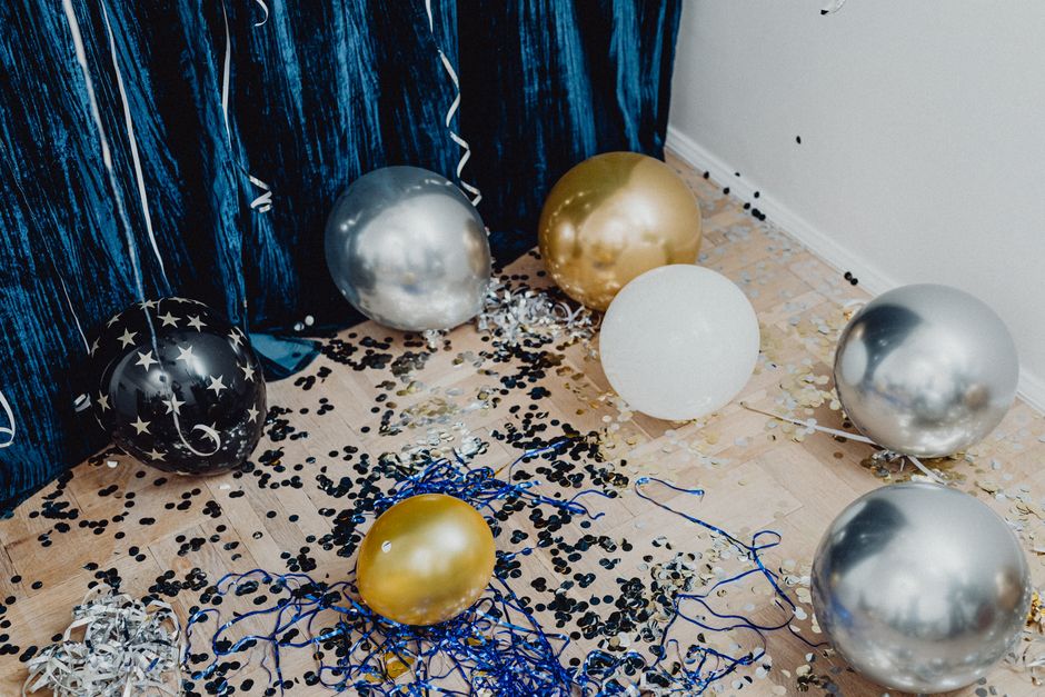 Coin photo décoré avec des ballons argentés, dorés et noirs, confettis au sol pour une soirée spéciale en couple.