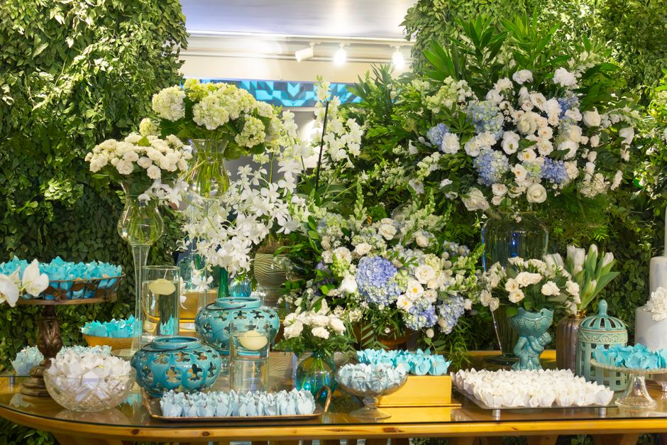 Centres de table fleuris avec des arrangements de fleurs blanches et bleues, décorés de vases et de douceurs.