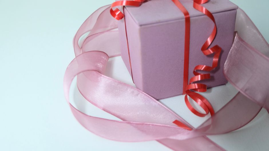 Cadeau violet avec un ruban rouge, entouré de satin rose, symbolisant la réconciliation après une dispute.