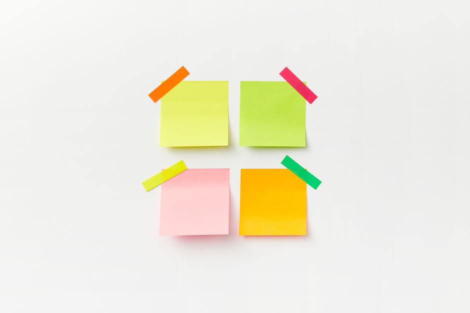 Quatre post-it de couleurs vives disposés sur un fond blanc, prêts pour une chasse au trésor à la maison.
