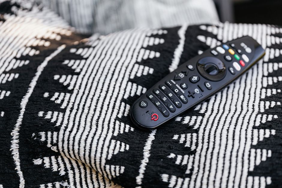 Télécommande posée sur un plaid noir et blanc, prête pour une soirée de comédies romantiques en couple.