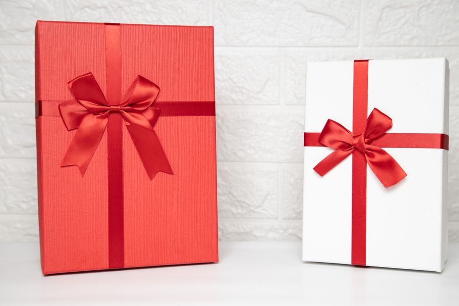 Cadeaux joliment emballés en rouge et blanc avec des rubans rouges sur un fond clair.