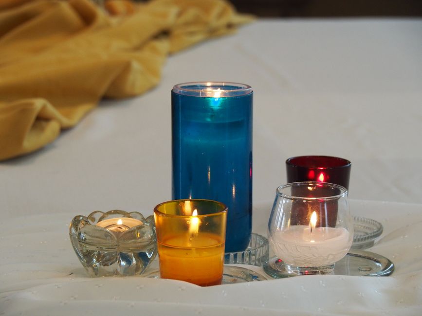 Bougies de différentes couleurs disposées sur une table, créant une ambiance romantique pour un dîner aux chandelles.