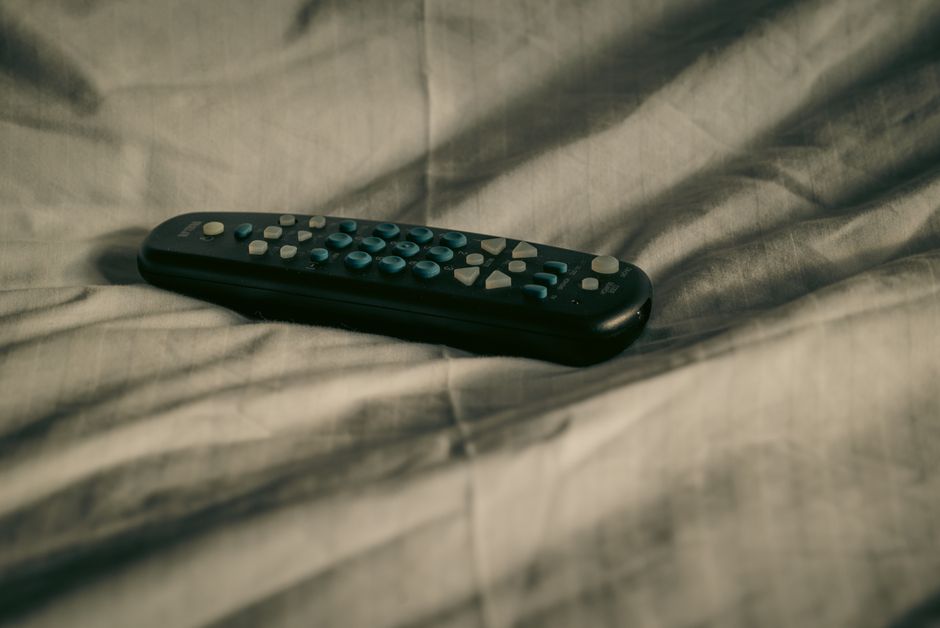 Télécommande posée sur un lit, suggérant une soirée cinéma romantique en couple.