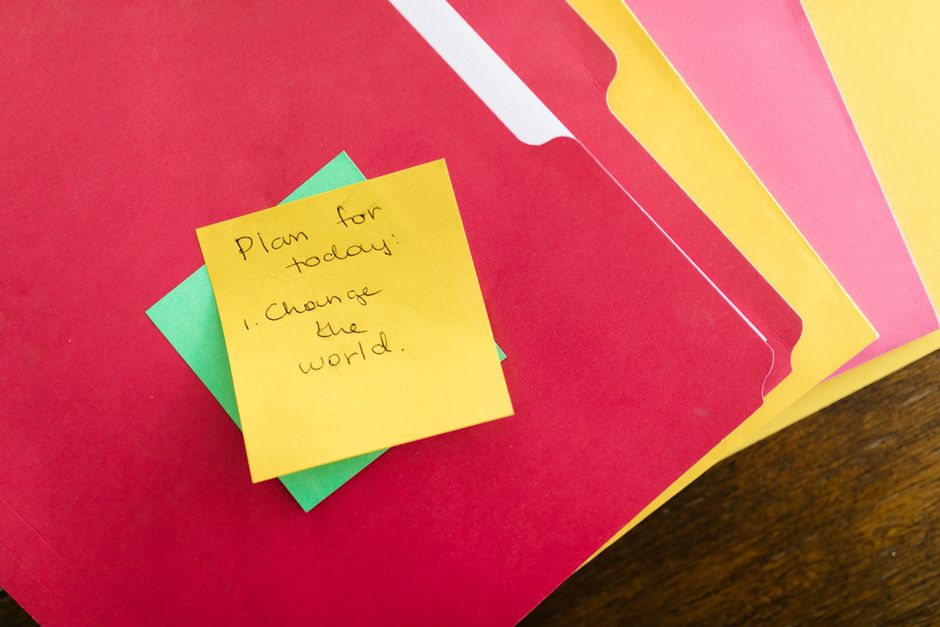 Post-it jaune avec un message inspirant sur un fond de dossiers colorés, suggérant des idées pour cacher des mots doux.