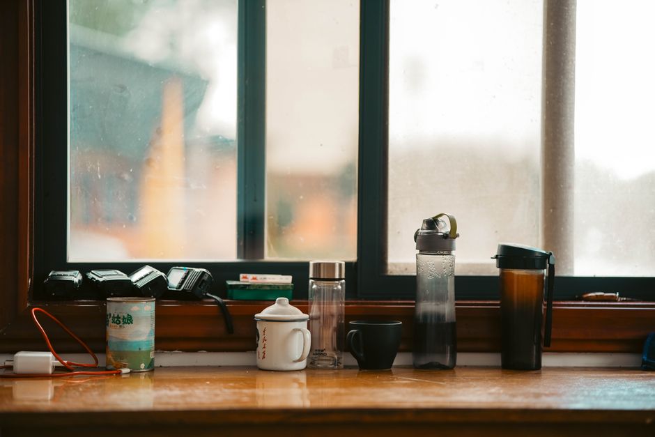 Des tasses et bouteilles sur un rebord de fenêtre, évoquant un moment de partage et de réconciliation.