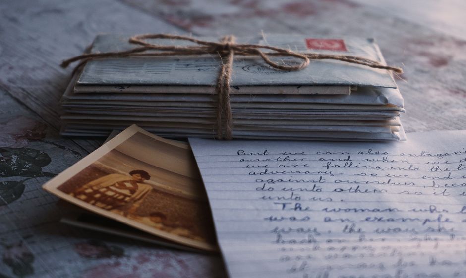 Enveloppes liées avec une ficelle, photo ancienne et lettre manuscrite sur une table en bois.